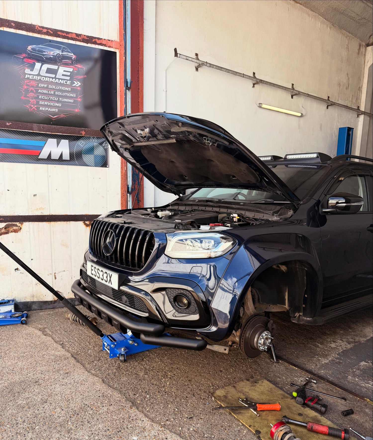 Mercedes-Benz car with open hood in a garage setting